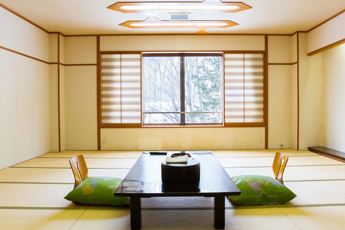 Ein traditioneller japanischer Raum mit Tatami-Böden, einem niedrigen Tisch und Shoji-Schiebetüren.