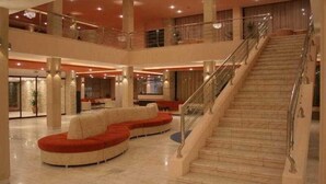 A spacious lobby with a central seating area, a staircase, and a second-floor balcony. - Paradiso (Mangalia)