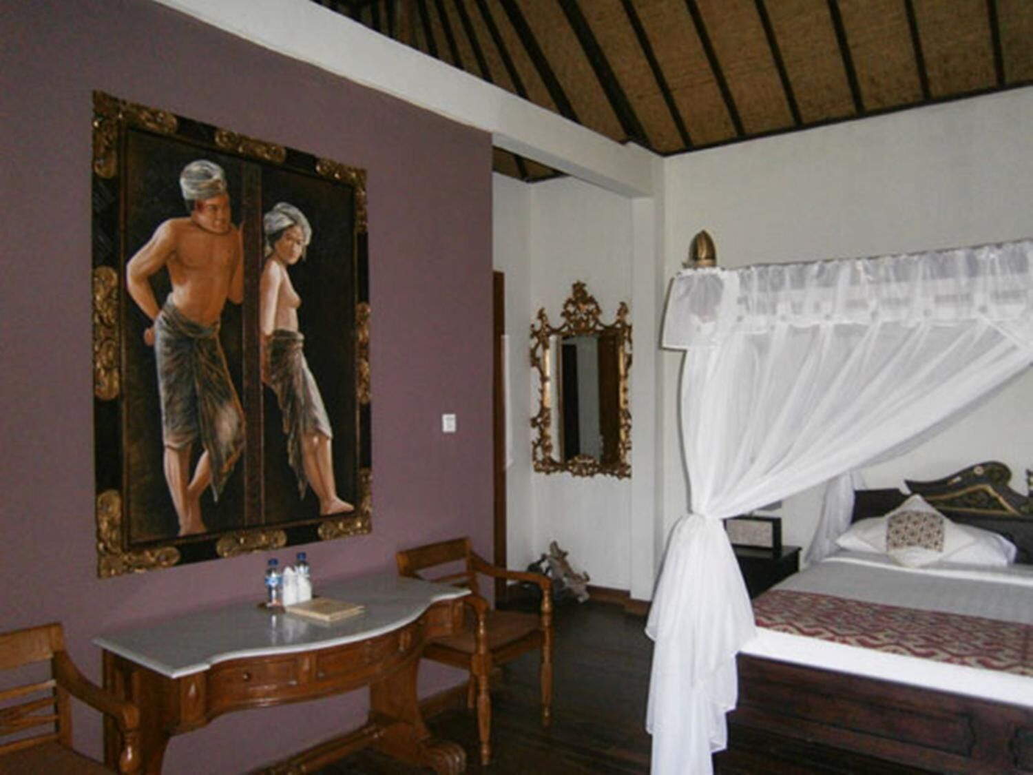 A bedroom with a bed, a bedside table, a chair, a mirror, and a painting on the wall.