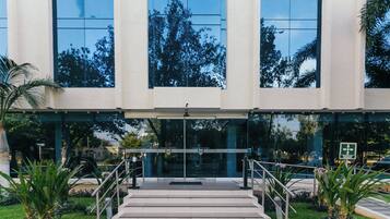 A hotel entrance with a glass facade, steps leading up to the door, and a sign indicating the hotel's name.