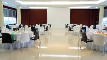 A large banquet hall with multiple round tables set for dining, arranged in rows.