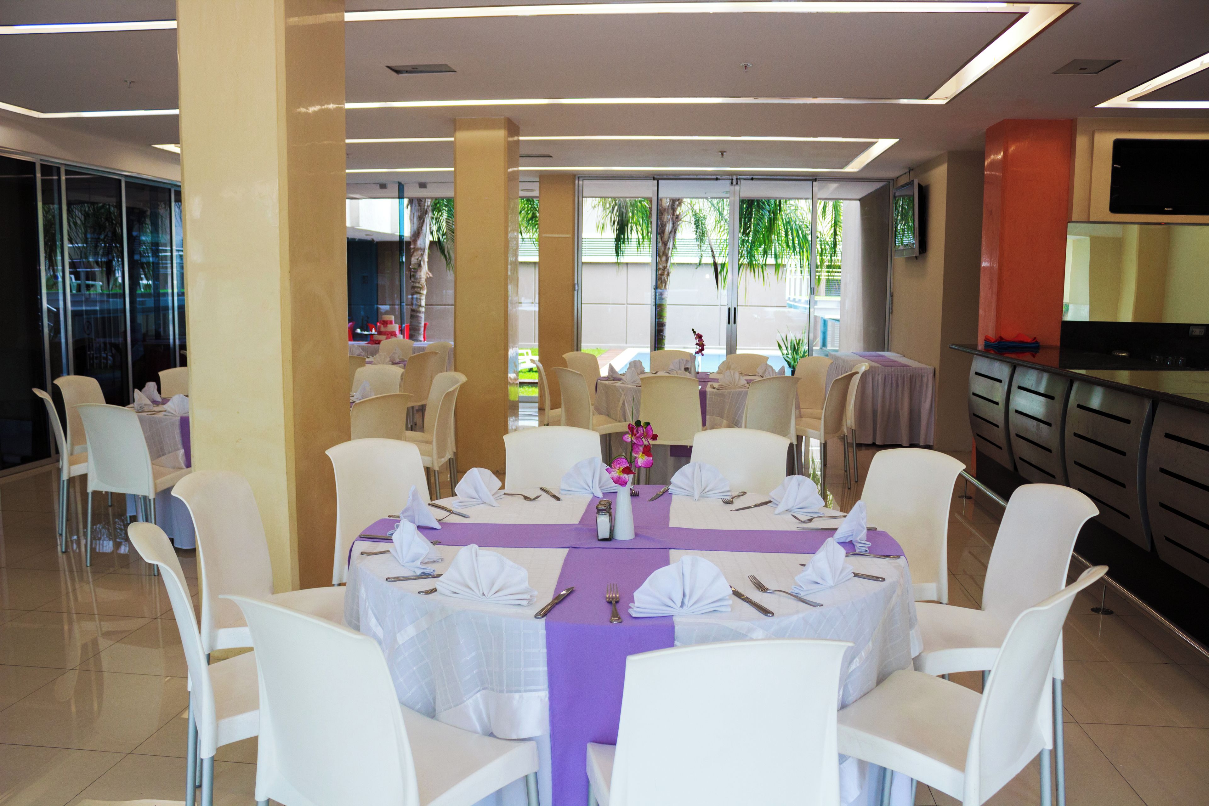 A dining area with round tables, white chairs, and purple tablecloths.