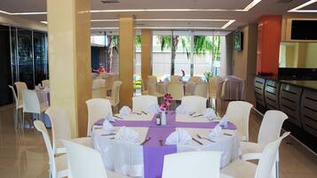 A dining area with round tables, white chairs, and purple tablecloths.