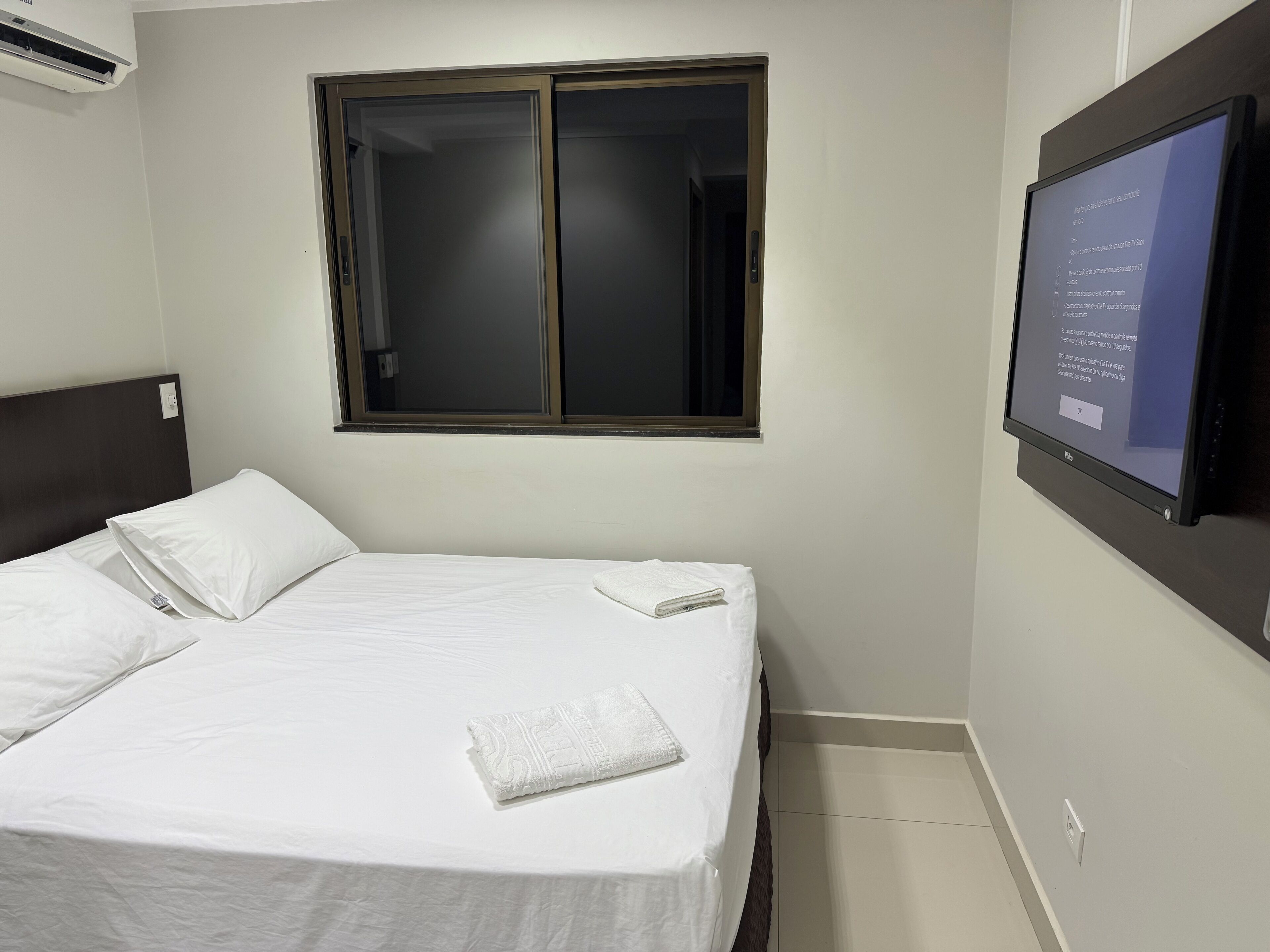 Una habitación de hotel con una cama, una ventana y un televisor fijado a la pared.