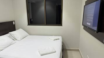 Una habitación de hotel con una cama, una ventana y un televisor fijado a la pared.