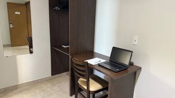 A small office space with a desk, chair, laptop, and a wardrobe.