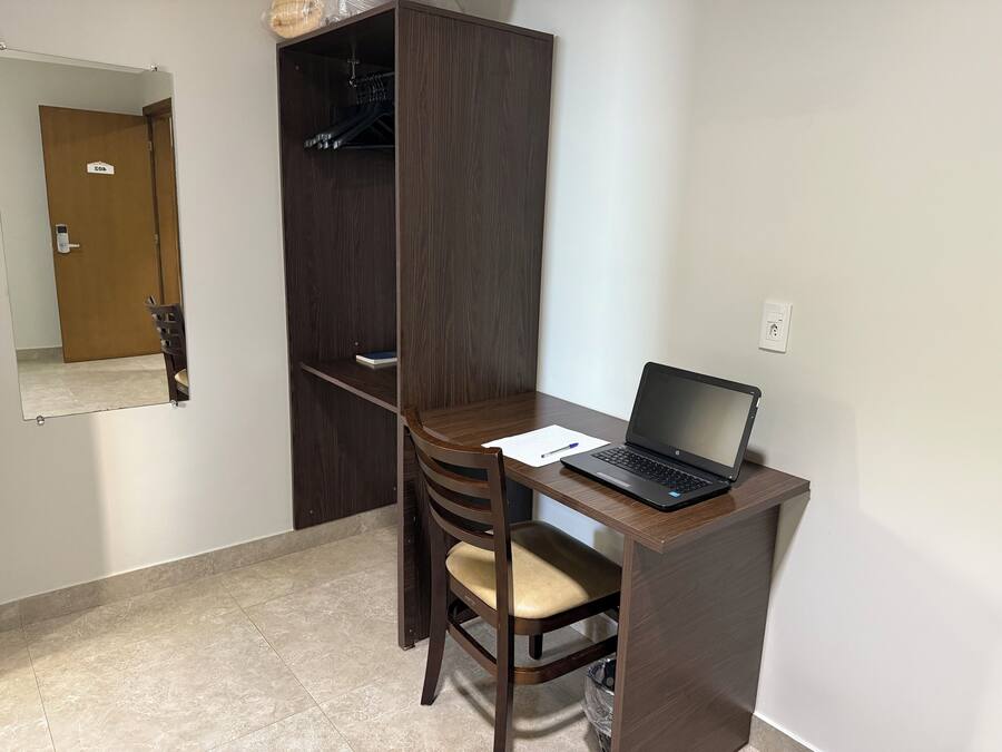 A small office space with a desk, chair, laptop, and a wardrobe.