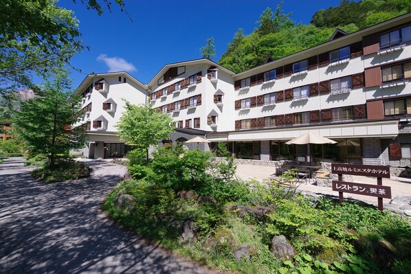 Un hotel con varios pisos, asientos al aire libre y un letrero que indica un restaurante.