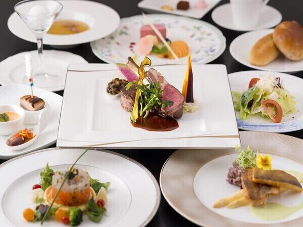 Variedad de platos emplatados, incluyendo un bistec con guarnición, una ensalada y otras entradas, lo que sugiere un ambiente de restaurante de alta cocina.