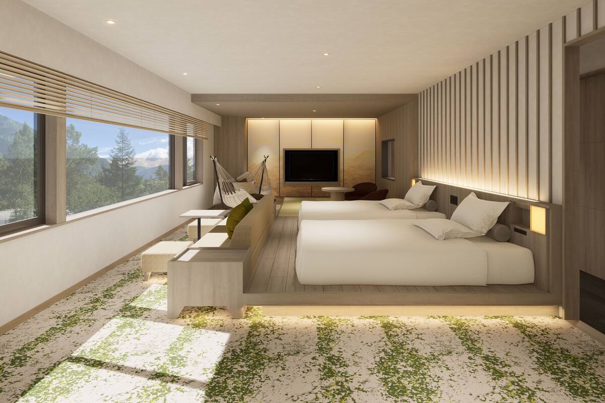 Quarto de hotel moderno com uma cama grande, área de estar com mesa, televisão e vista para o exterior.