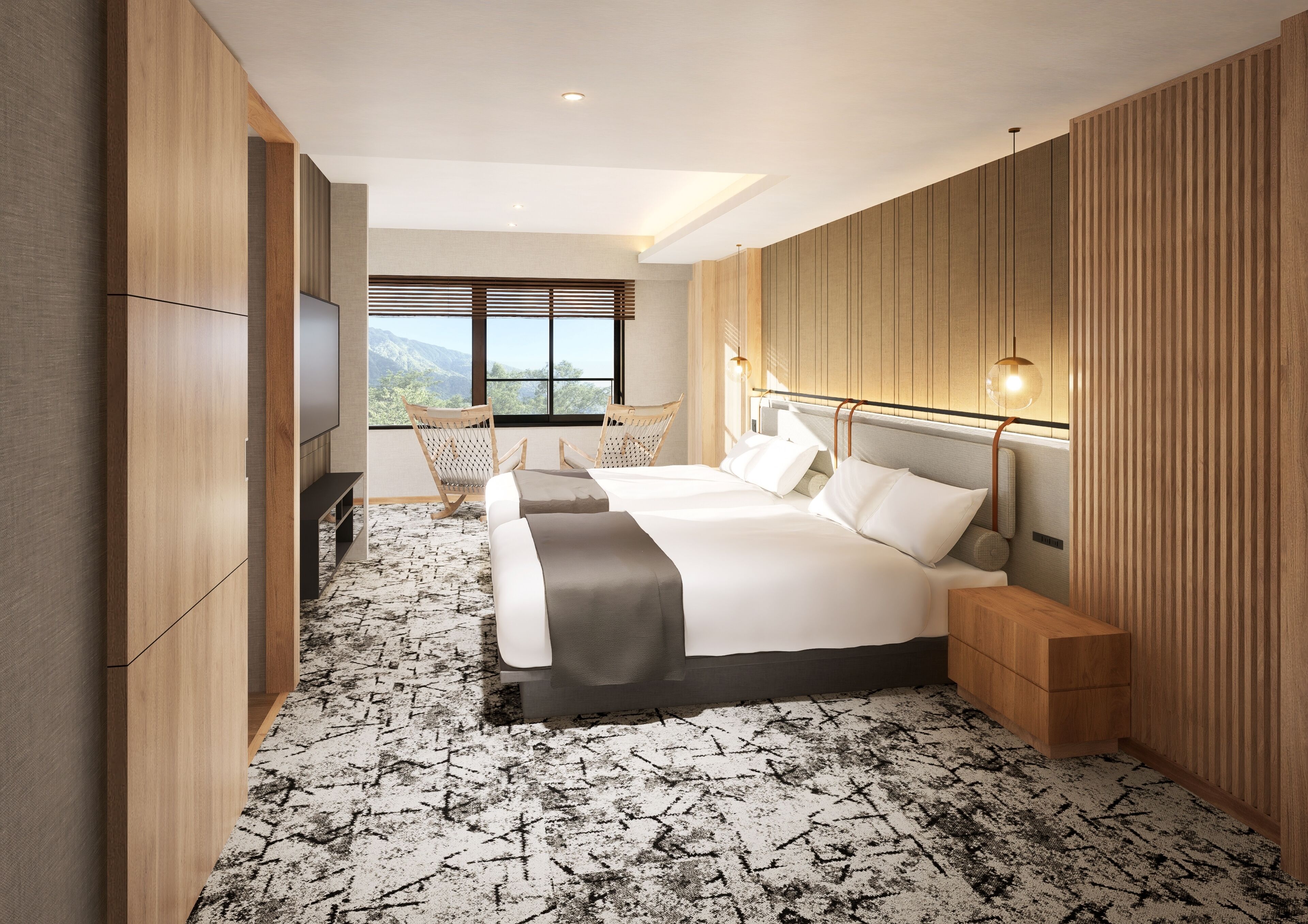 A modern hotel room with a large bed, two chairs, a desk, and a view of mountains through the window.