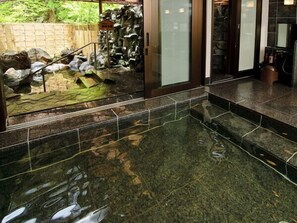 A spa area with a stone-tiled floor, a small pool, and a stone wall. - Kamikochi Lemeiesta Hotel (Matsumoto)