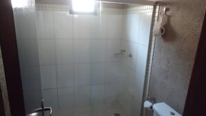 A small, enclosed shower area with a glass door, a toilet, and a towel rack. - Pantanal Hotel (Miranda)