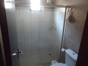 A small, enclosed shower area with a glass door, a toilet, and a towel rack.