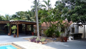 A pool area with a pergola, palm trees, and a tiled patio. - Pantanal Hotel (Miranda)