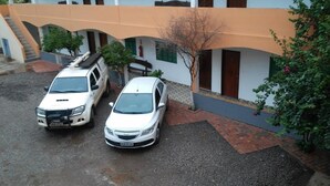A building with two cars parked in front, a staircase, and a tree. - Pantanal Hotel (Miranda)