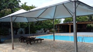 A covered outdoor area with a pool, stone flooring, and a table with chairs. - Pantanal Hotel (Miranda)
