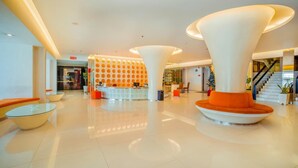 A modern lobby with a reception desk, seating areas, and a staircase. - Cemerlang (Bandung)