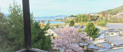 Une ville japonaise traditionnelle, avec une rivière, des cerisiers en fleurs et une pagode.