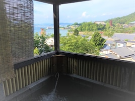 Una habitación con vistas al agua, edificios y vegetación.