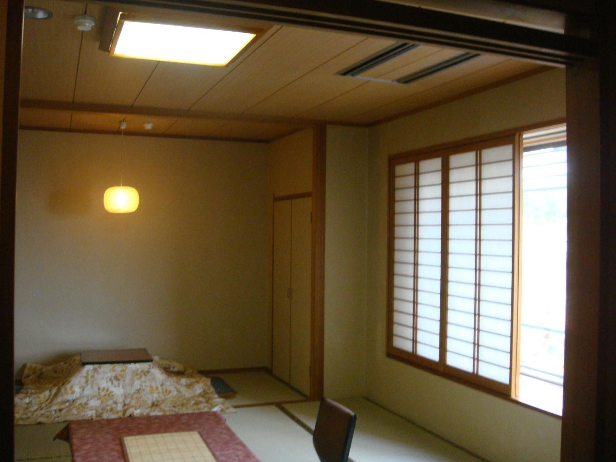 A traditional Japanese room with tatami flooring, a futon bed, a shoji screen, and a ceiling fan.