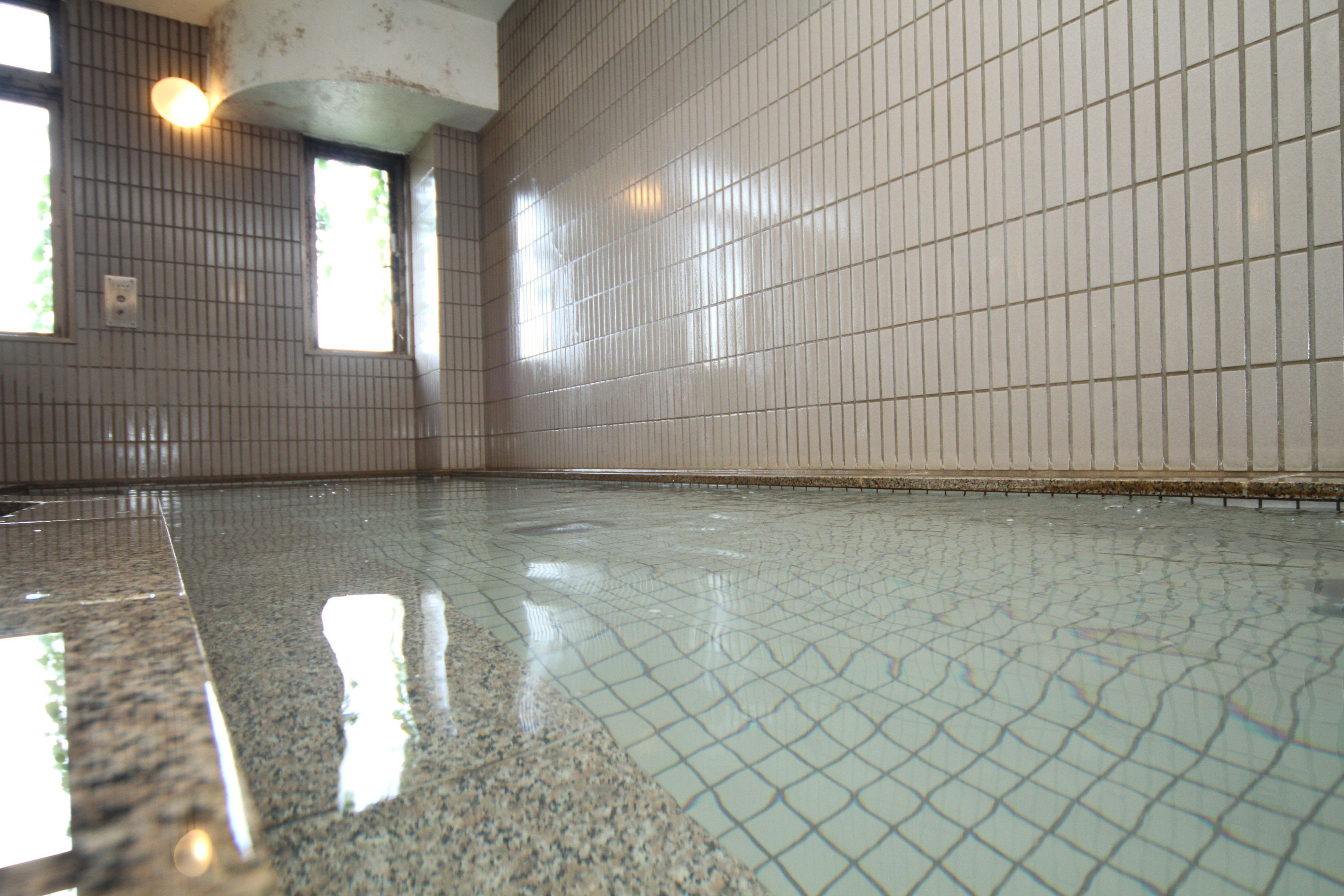 Uma piscina interior ampla, com paredes em azulejo e piso lustroso.