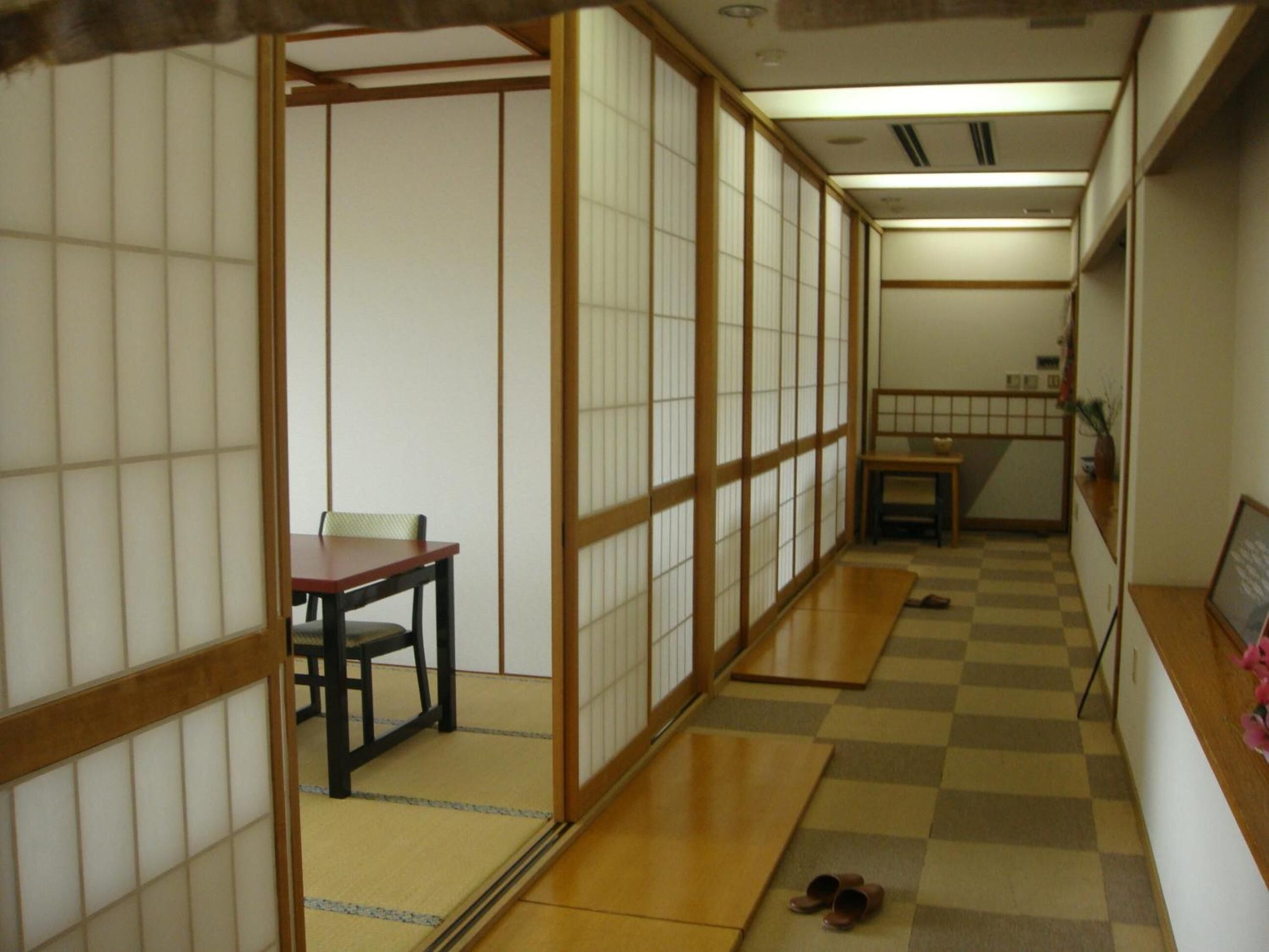 A traditional Japanese room with tatami flooring, a low table with a chair, and sliding doors.