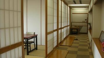 A traditional Japanese room with tatami flooring, a low table with a chair, and sliding doors.