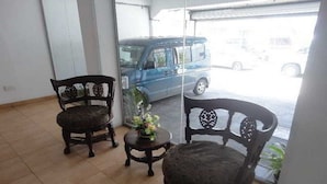 Une pièce comprenant deux fauteuils en bois richement décorés et une petite table sur laquelle est posé un vase de fleurs.