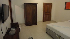 Une chambre à coucher comprenant un lit, une armoire, un téléviseur et un bureau avec un ordinateur.