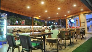 An indoor restaurant with wooden ceiling and walls, tables, chairs, and a TV screen. - Happy Homes Apartments (Alanya)