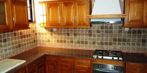 Una cocina con armarios de madera, salpicadero de azulejos y una estufa.
