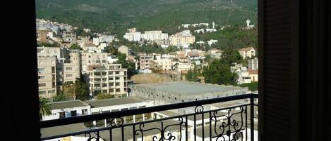 A balcony with a view of a cityscape, including buildings and mountains.