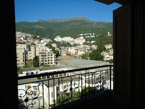 Un balcón con vistas a un paisaje urbano, incluyendo edificios y montañas.