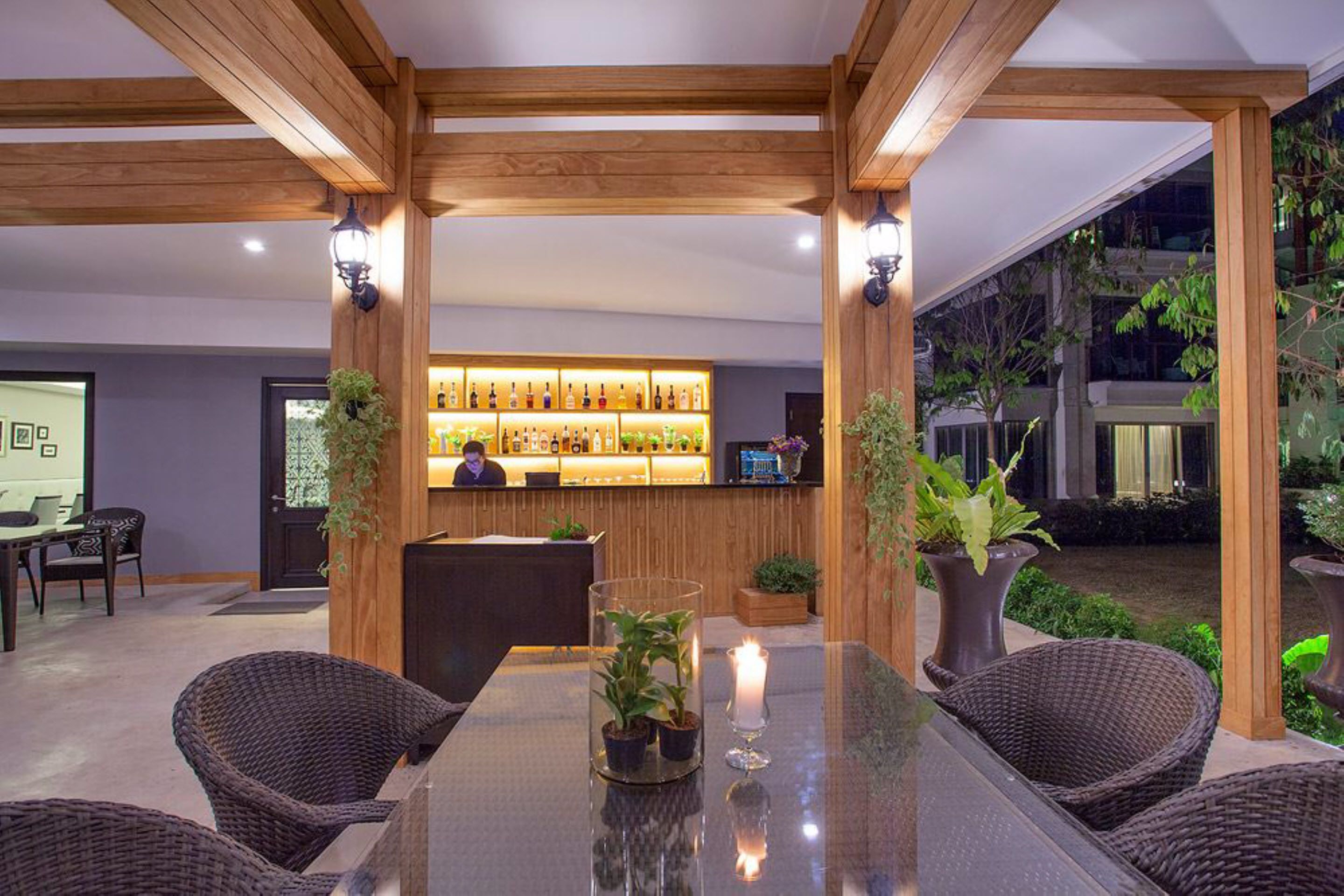 A reception area with a bar, wicker chairs, and potted plants.
