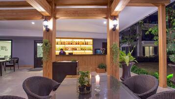 A reception area with a bar, wicker chairs, and potted plants.