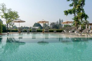 Una piscina al aire libre, sillones reclinables de piscina