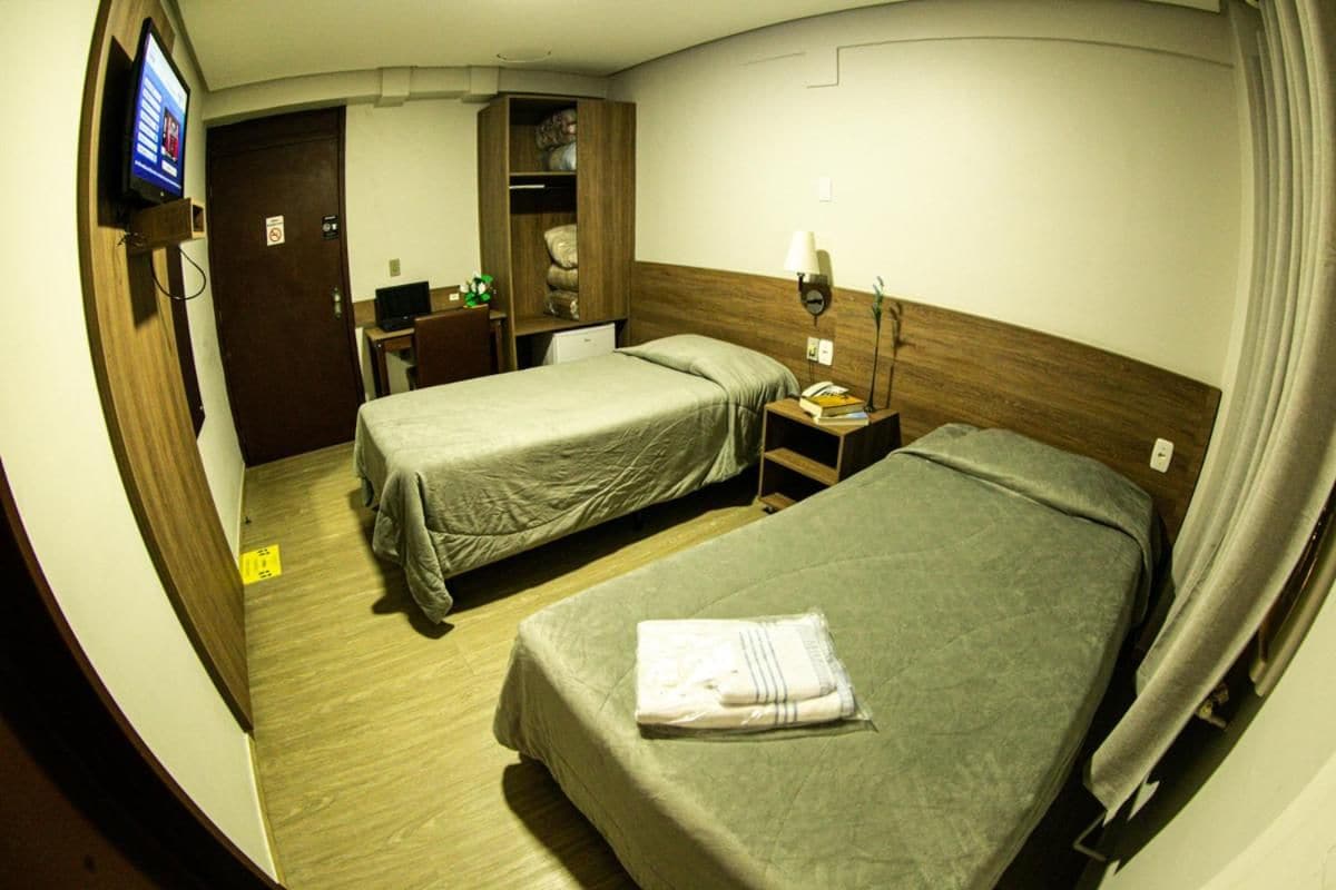 Una camera d'albergo con due letti, una televisione, una scrivania con un computer e un armadio.