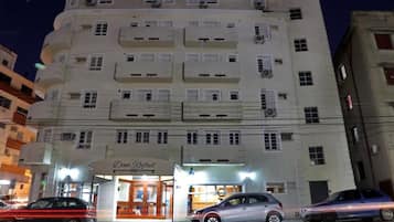 Un hotel de varios pisos con acceso a nivel de calle, un cartel visible que dice 'Dom Rafael' y varios coches estacionados en la entrada.