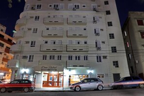 A multi-story hotel with a ground-level entrance, a visible sign for 'Dom Rafael', and several parked cars in front.
