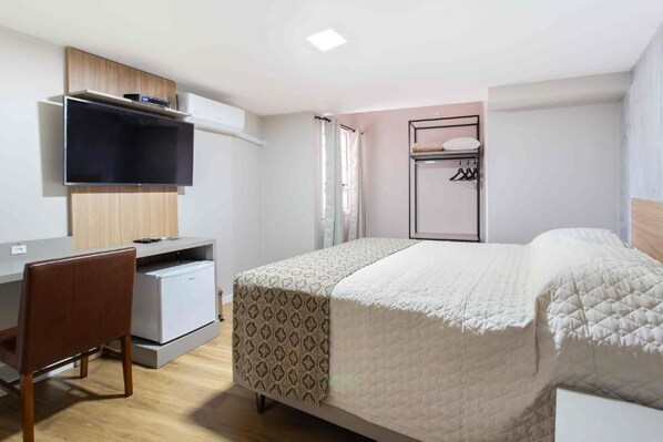 A bedroom with a bed, a desk, a chair, a TV, and a wardrobe.