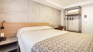 A hotel room with a bed, a bedside table with a phone, a coat rack, and a wardrobe. - Hotel Dom Rafael Executivo (Santa Maria)