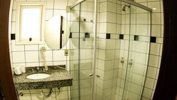 A bathroom with a glass-enclosed shower, a sink with a countertop, and a toilet.