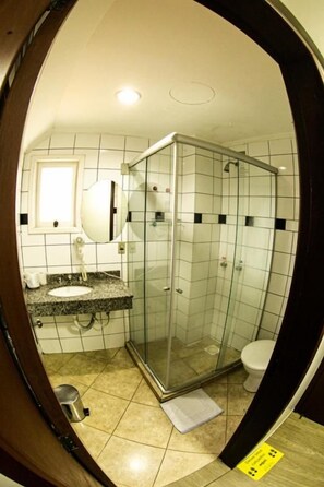 A bathroom with a glass-enclosed shower, a sink with a countertop, and a toilet.