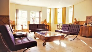 A spacious living room with a large wooden coffee table, several cushioned chairs, and a sofa. - Hotel Dom Rafael Executivo (Santa Maria)