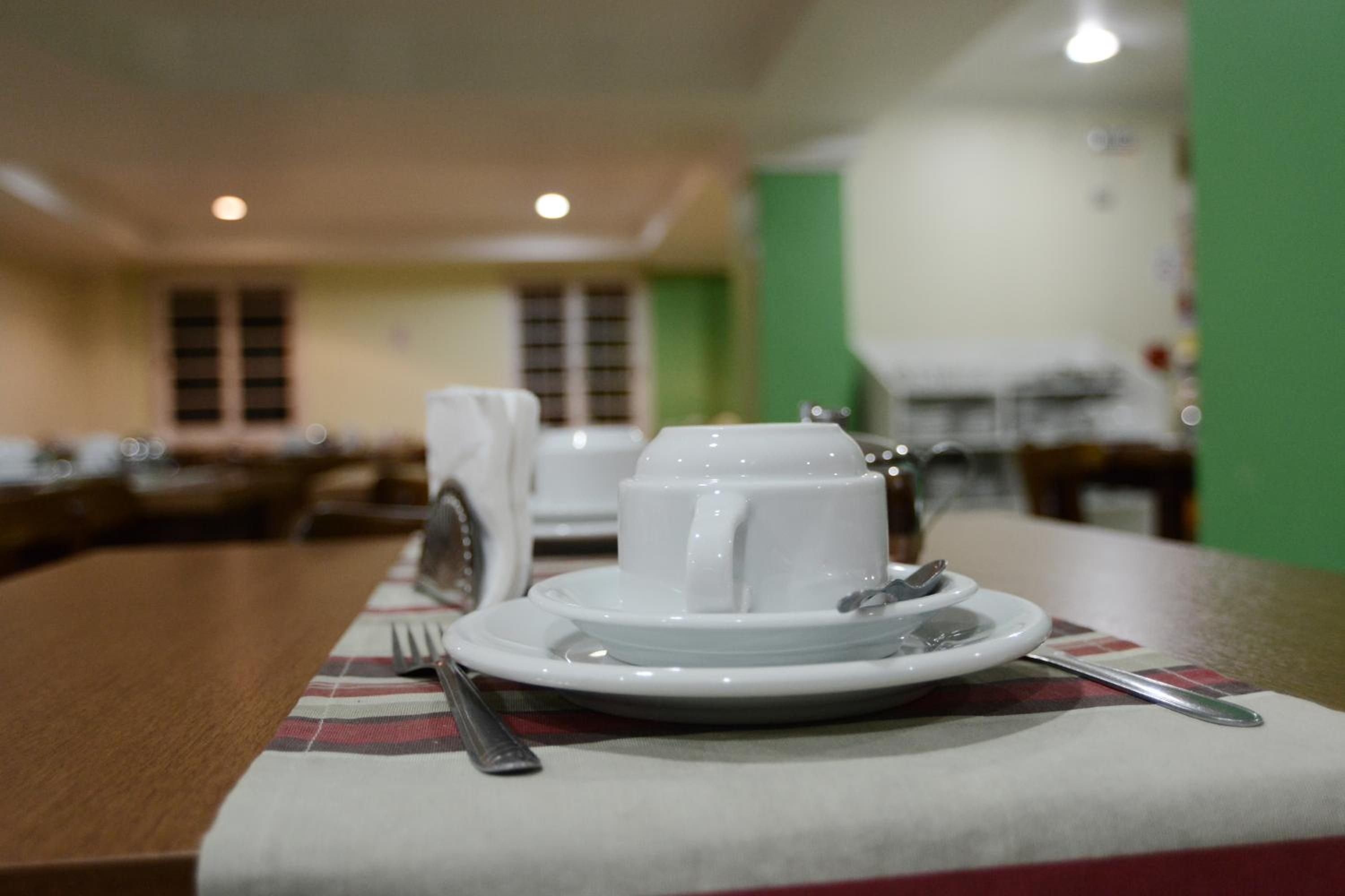 A dining table with a white plate, a cup, and a fork.