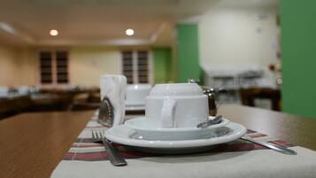 A dining table with a white plate, a cup, and a fork.