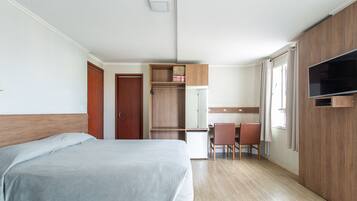 A bedroom with a bed, a desk, a chair, a TV, and a wardrobe.