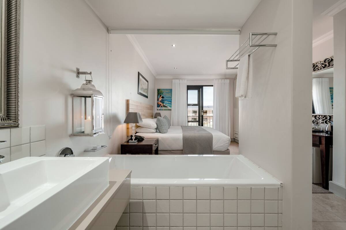 A modern hotel bathroom with a large bathtub, a separate sink, and a mirror.