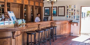 Un espace bar avec des tabourets en bois, un comptoir où sont exposées des bouteilles de vin et un tableau affichant le menu.
